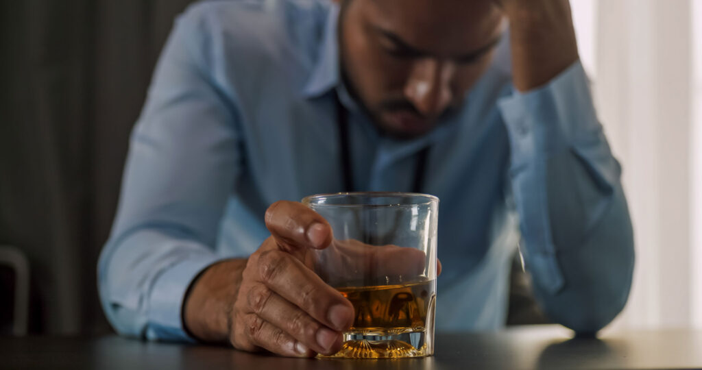 Young professional drinking alcohol and needs help for alcohol addiction.