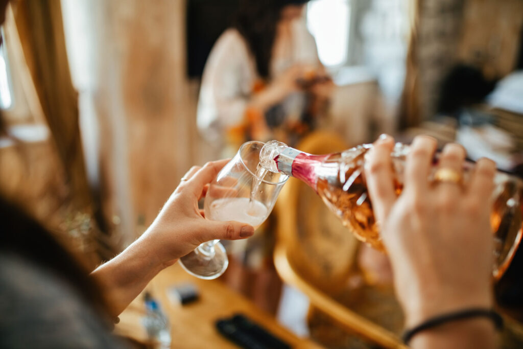 Woman with alcohol dependence pouring champagne in a glass.