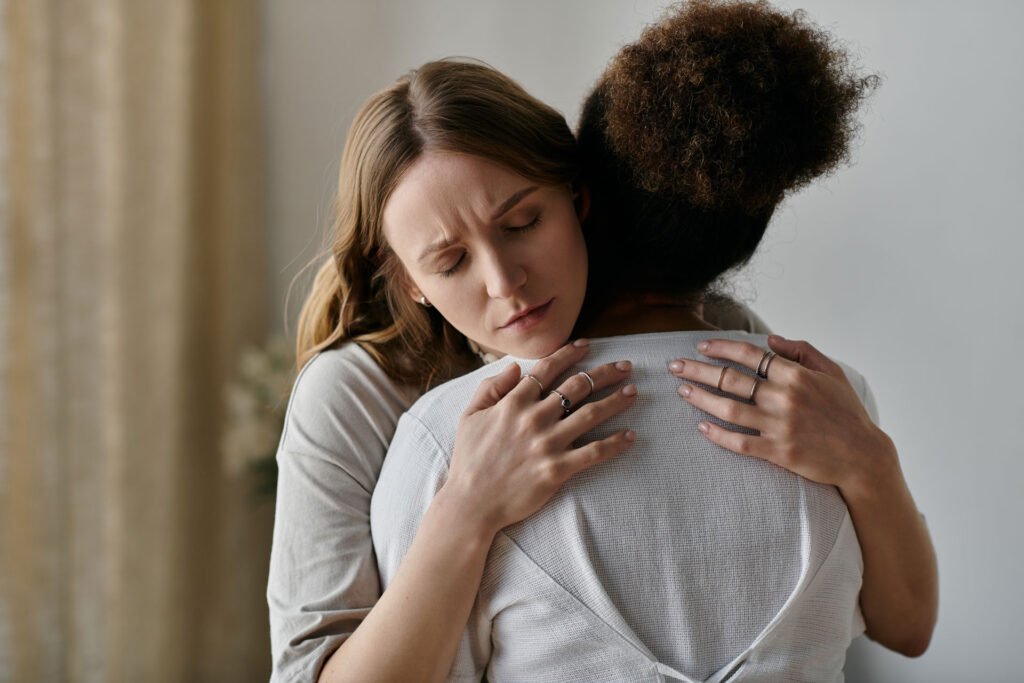 A woman in grief being comforted by other woman.