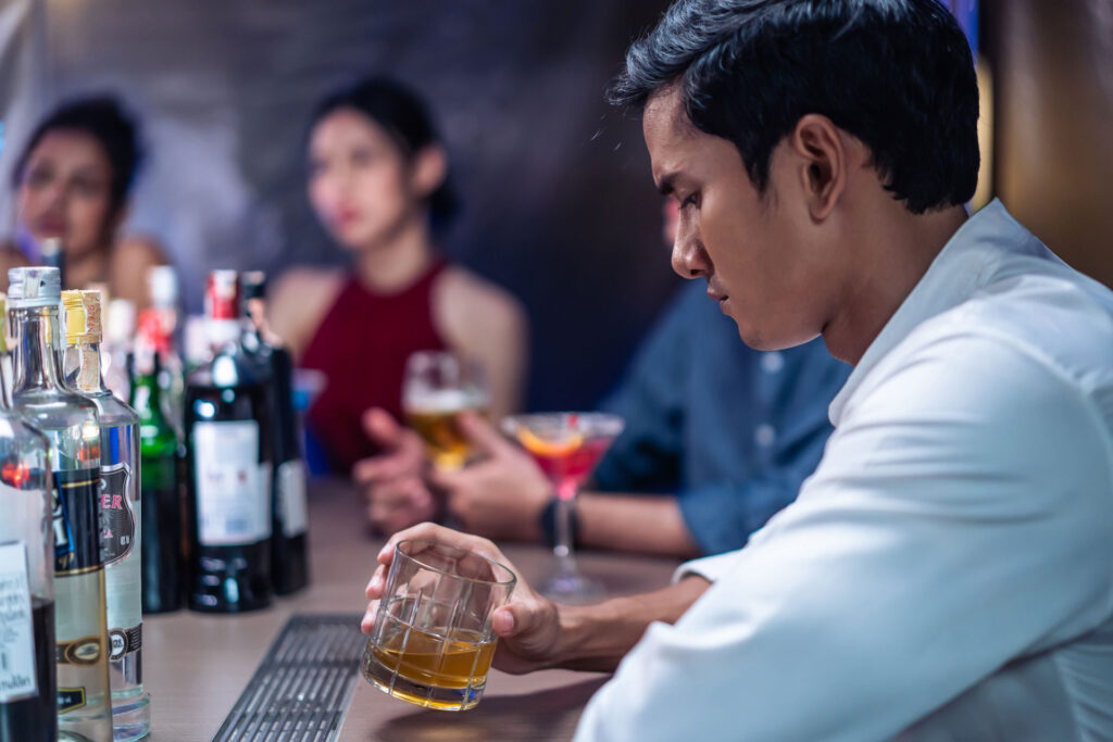 Asian man feeling depressed while drinking.