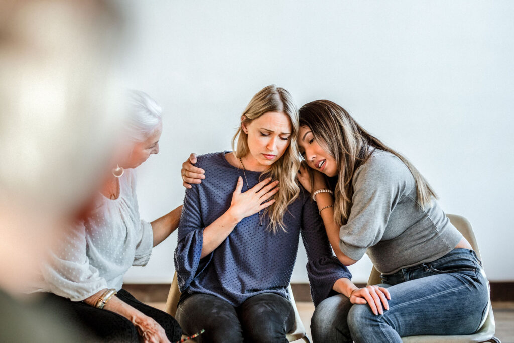 Woman comforting each other to lessen the effect of grief on mental health.