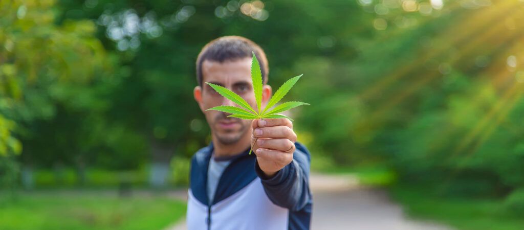 A man with cannabis use disorder holding a cannabis leaf outdoor.