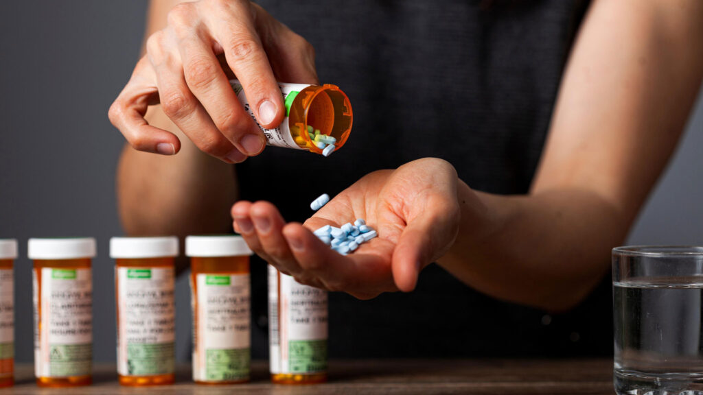 Person with prescription drug abuse pouring medicines.