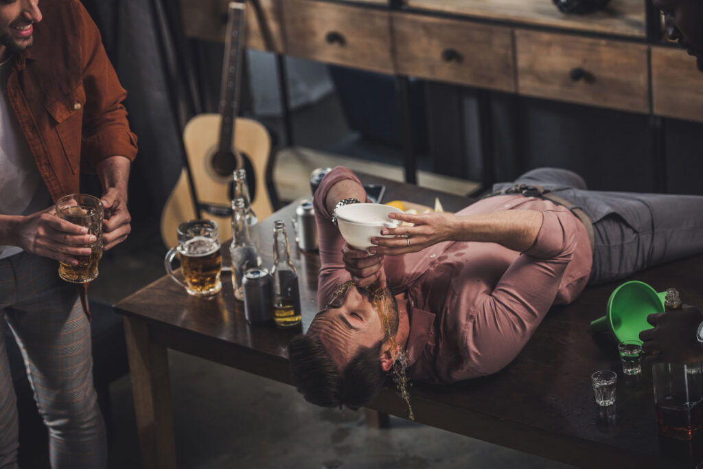 Young man with alcohol addiction lying in table.