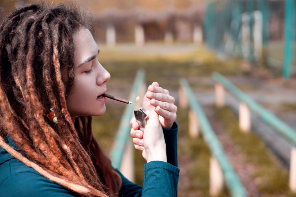 Young woman with cannabis addiction smoking a joint outdoor.