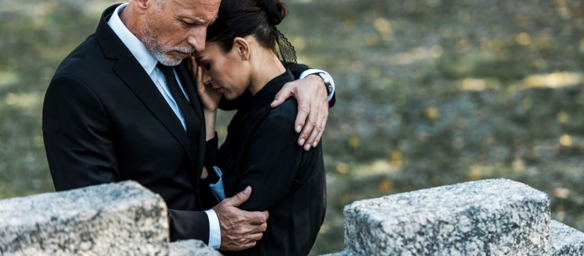 Senior man hugging a woman in grief.