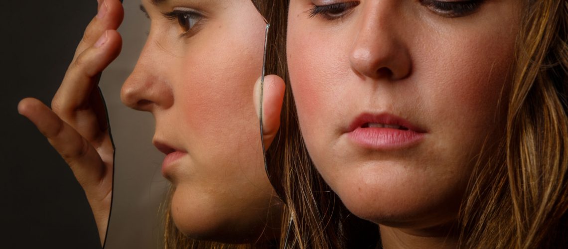 Young woman with reflection in mirror.