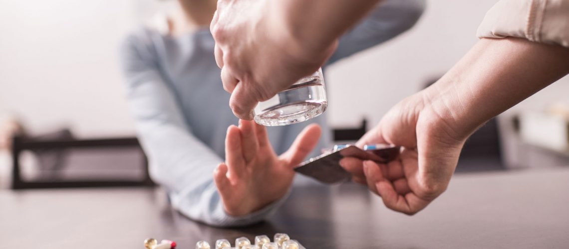 Someone bringing a glass of water to a woman.