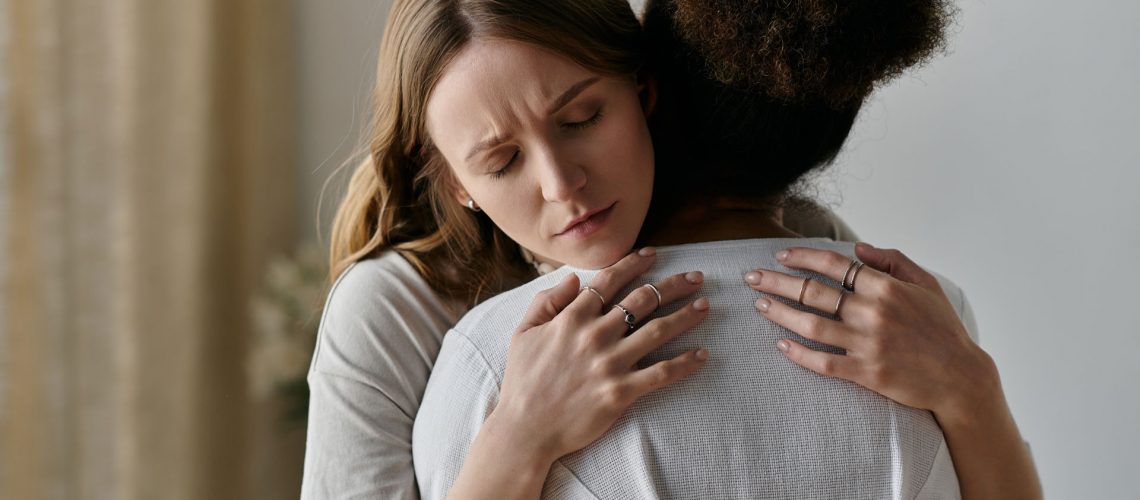 A woman in grief being comforted by other woman.